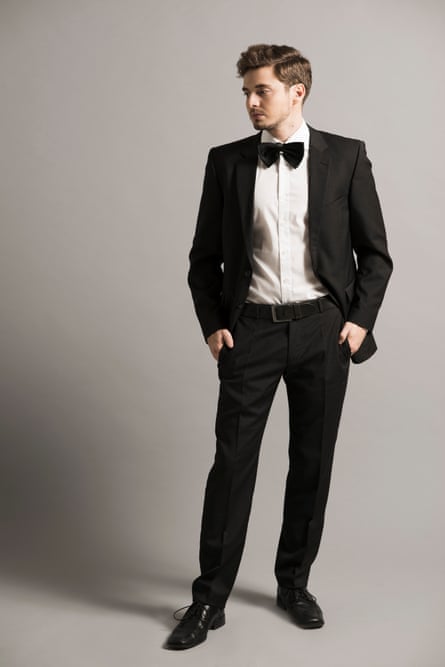 A twentysomething man with his hands in his pockets wearing a dinner jacket and bow tie