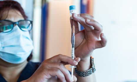heathcare worker draws vaccine from a vial