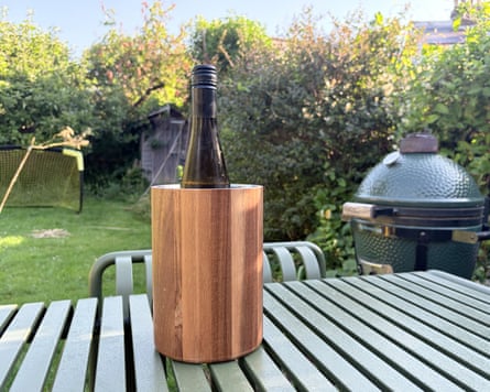 A bottle of wine in an AdHoc wine cooler on a garden bench.