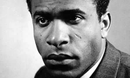 A close-up black and white photograph of Frantz Fanon staring just past the camera