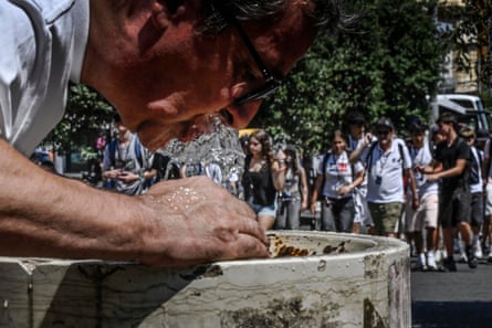 A man drinks from a fountain during hot weather in Naples.