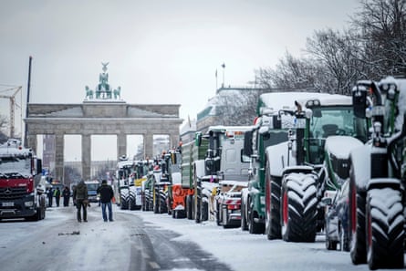 Queue of snow-covered tractors on the road with the Brandenburg gate in the background