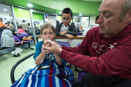 A man helps a boy use an asthma pump on a hospital ward