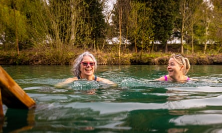 Two smiling women wild swimming in river or lake