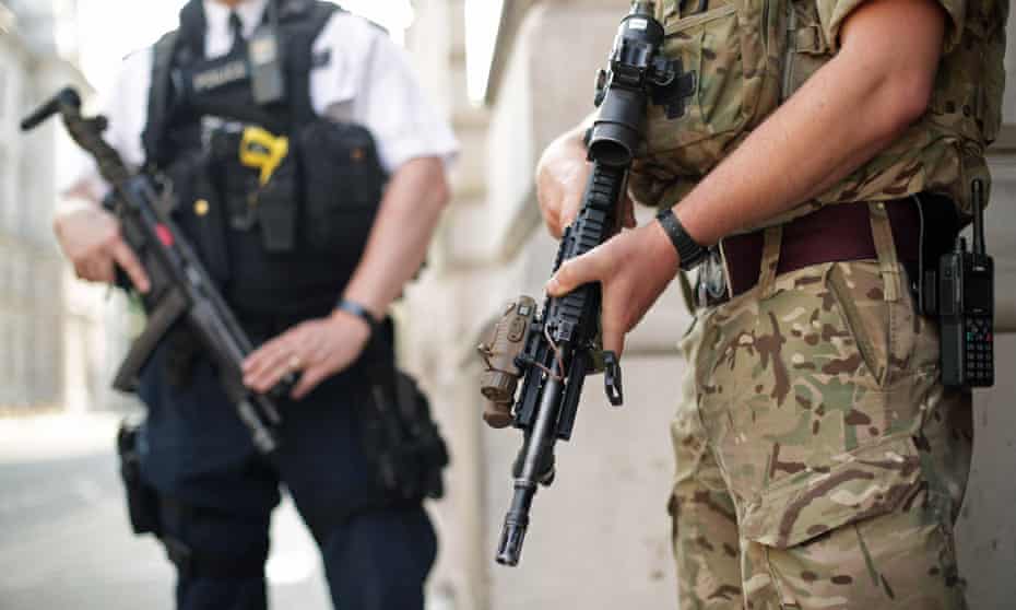 The torsos of an armed police officer and a soldier in khaki uniform