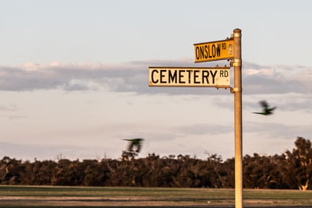 A yellowed street sign for Cemetery Road and Onslow Road, covered in dusty in the twilight
