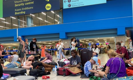 Travellers sit on the floor of the airport