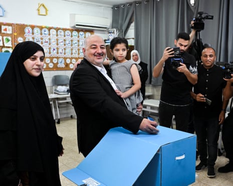 Abbas smiles, holding his daughter, as he casts his vote at a polling station.