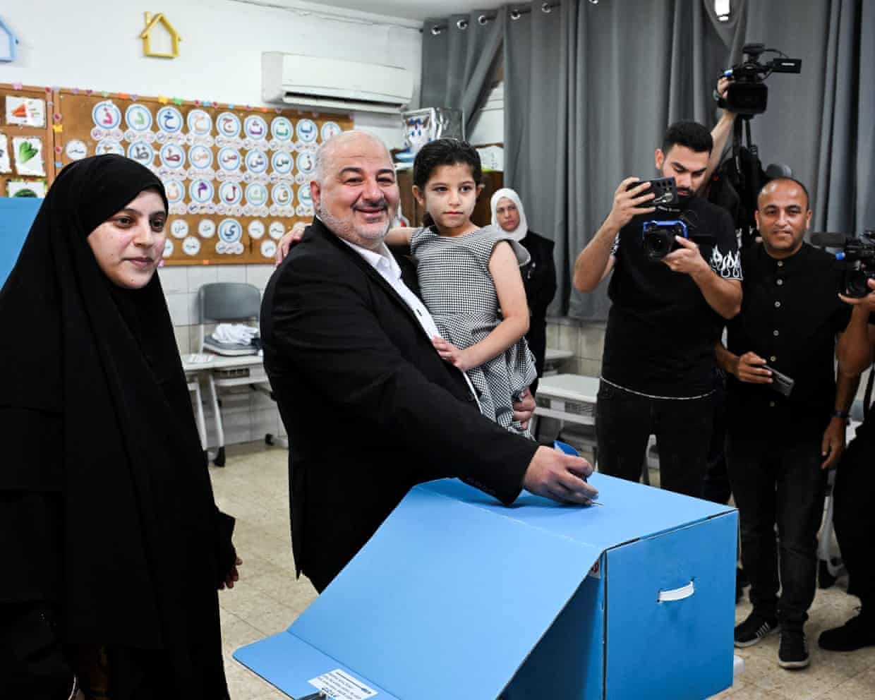 Abbas smiles, holding his daughter, as he casts his vote at a polling station.