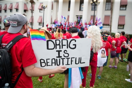 a person holds a sign that reads ‘drag is beautiful’