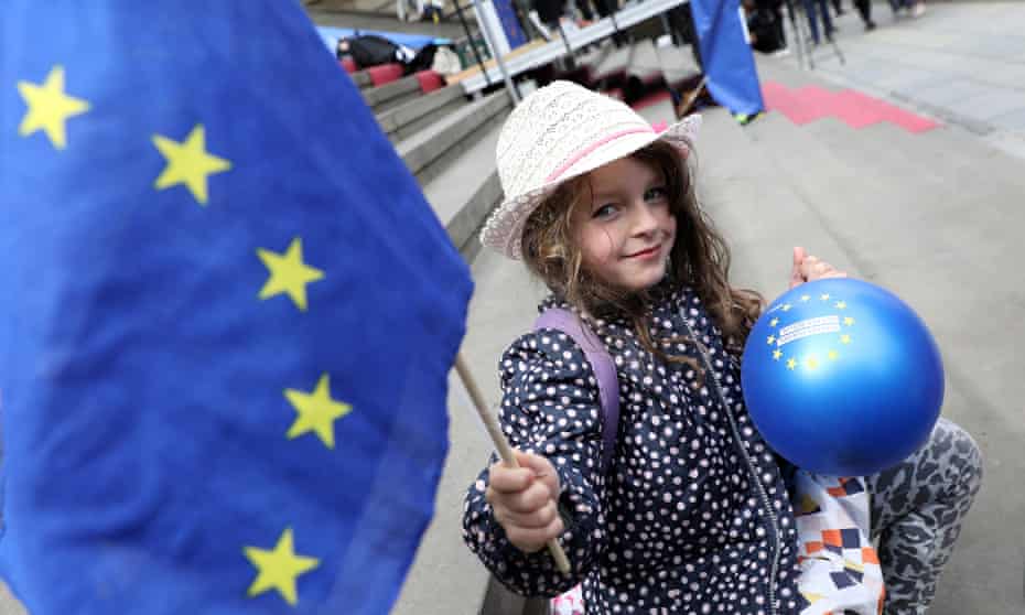 A child waves an EU flag and holds a balloon with the EU stars on it