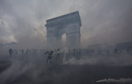 The arc de triomphe surrounded by smoke and gilet jaunes protesters