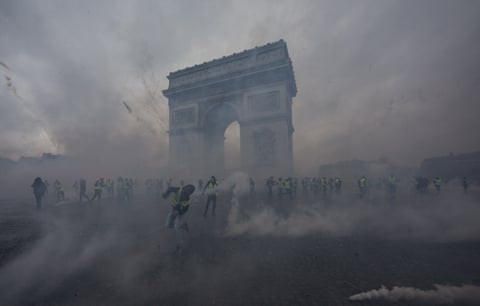 The arc de triomphe surrounded by smoke and gilet jaunes protesters