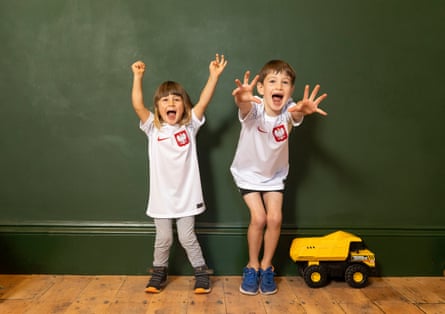 England’s united nations of football: 32 teams, one World Cup – and a lot of excited kids | World Cup 2022 24 Bruno and George Taylor looking very happy and excited, wearing white Poland shirts against a dark green wall, with a yellow Tonka truck beside them on the wooden floor