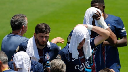 Paris St Germain’s Khvicha Kvaratskhelia, Fabian Ruiz and others cool down during a break in play; they have white towels around their necks and heads