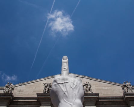 Giant sculpture of a finger pointing skyward in front of a formal, old looking building