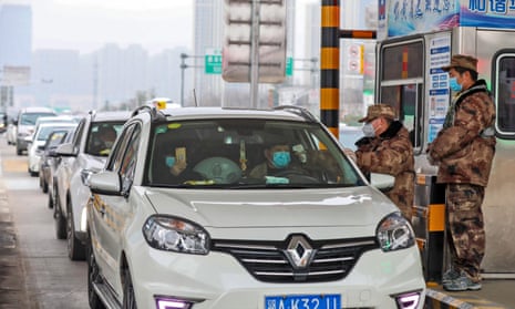 A militia member checks the body temperature of a passenger on a vehicle at an expressway toll gate in Wuhan, Hubei province, on Thursday.