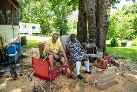 a man and a woman sitting on chairs outside surrounded by trees