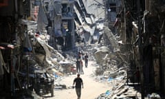 People walking along narrow road between destroyed buildings