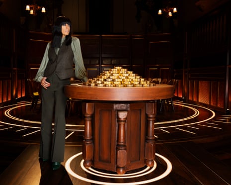 Claudia Winkleman leaning on a table with gold coins on it