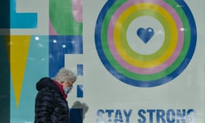 A woman wearing a face mask walks by a poster in a shop window in Dún Laoghaire, south Dublin.