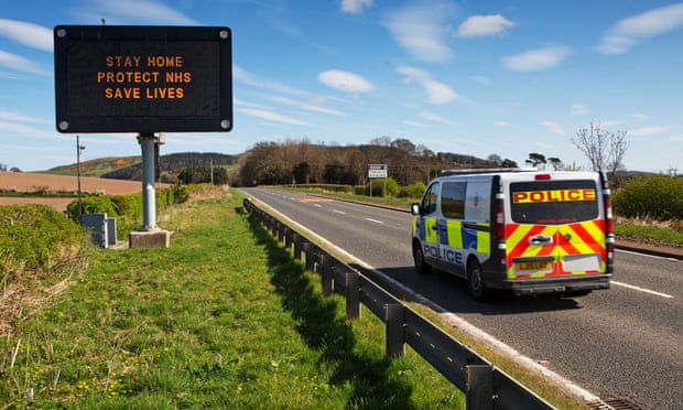 A police van drives past a road sign saying: ‘Stay home, protect the NHS, save lives’ neer Dundee.