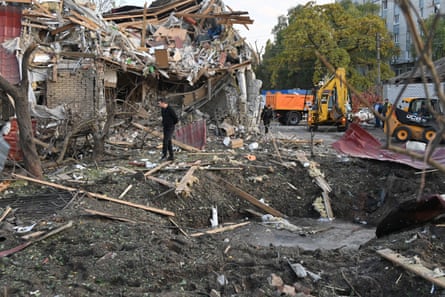 A man walks through rubble beside a crater left by a drone strike in Kharkiv