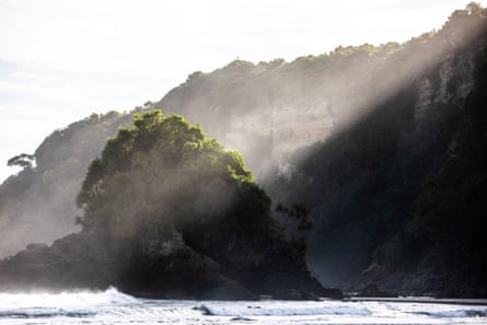 A shaft of late afternoon light hits vegetation on an outcrop at the end of Sunubari beach, Sumba, Indonesia