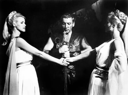 Black-and-white image of the twins standing face to face, clasping hands, as a man stands with a sword between them.