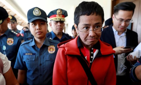 ‘In the face of multiple threats, criminal charges and two arrests, Maria Ressa has continued to speak out.’ Maria Ressa is escorted by police after posting bail.