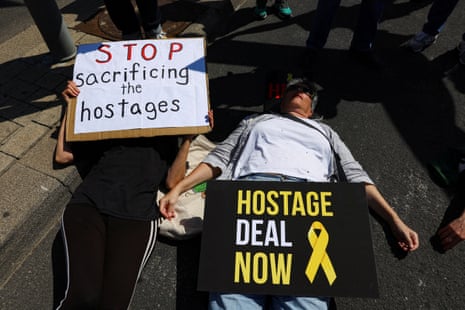 People lie in the street blocking traffic during a protest calling for a ceasefire deal and the release of Israeli hostages, outside the US embassy branch office in Tel Aviv, Israel, on Friday. The signs laying on top of them read ‘stop sacrificing the hostages’ and ‘hostage deal now’.