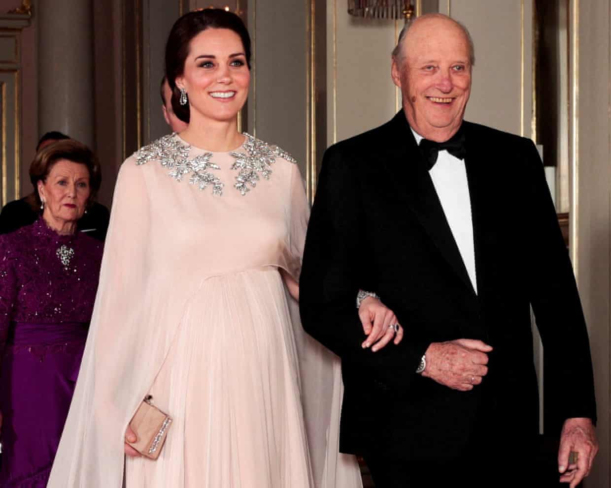 Princess Catherine in a flowing Alexander McQueen gown walking arm in arm with King Harald, wearing a tuxedo