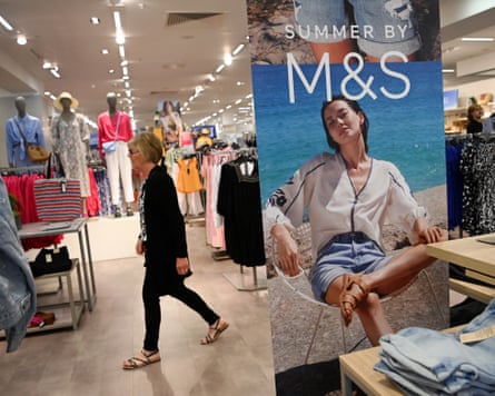 A shopper passes a display of jean shorts in an M&S store