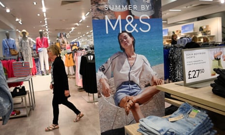 A woman walking through the clothes section of an M&S shop