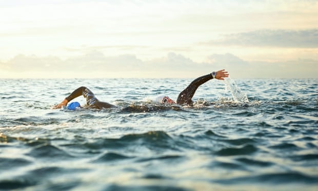 Femmes nageant dans la mer au coucher du soleil.