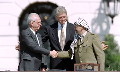 Yitzhak Rabin and Yasser Arafat shake hands outside the White House, with Bill Clinton standing behind them.