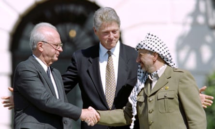 The Israeli prime minister Yitzahk Rabin and PLO leader Yasser Arafat shake hands for the first time (watched by Bill Clinton) after signing the historic Oslo peace accords in 1993.