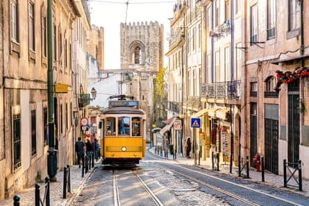 Street in Lisbon old town with yellow tram and Lisbon Cathedral in the background
