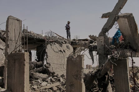 A man with a helmet and a gun stands on the remains of a floor