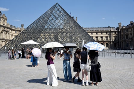 People outside the Louvre in Paris shade themselves with umbrellas