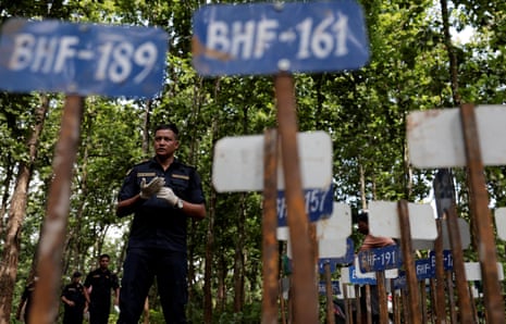 A police officer stands near identification number tags for bodies at the Devghat mass burial site for victims of deadly flash floods and mudslides, in Chitwan, Nepal.