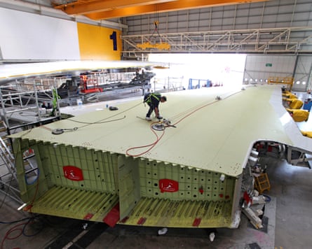 An employee inspects the surface of an Airbus A380 wing
