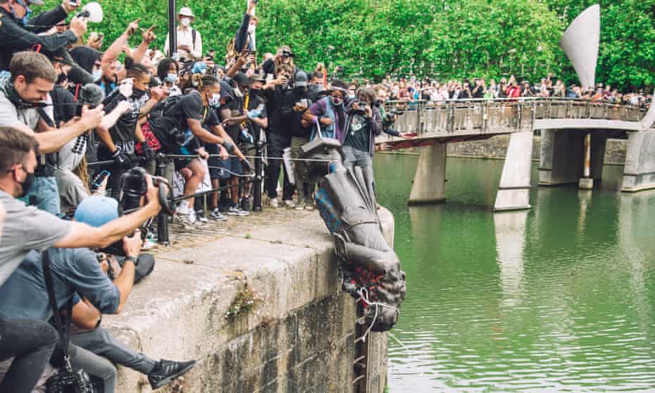 The statue of Colston is pushed into the river Avon, in front of cheering protesters.