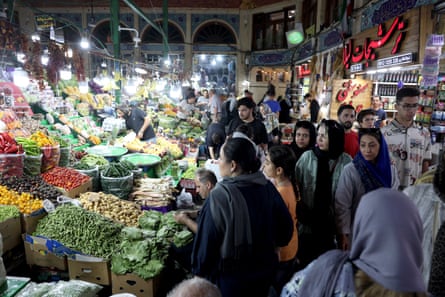 A group pf people at a stall selling vegetables at a bazaar in Tehran.