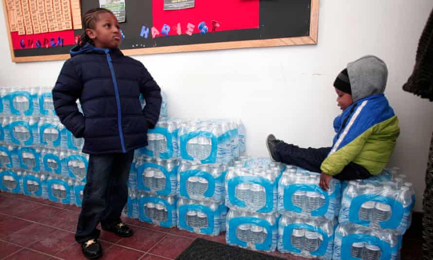 Justin Roberson (L), age 6 and Mychal Adams, age 1, wait on a stack of bottled water in Flint, Michigan, 2016.