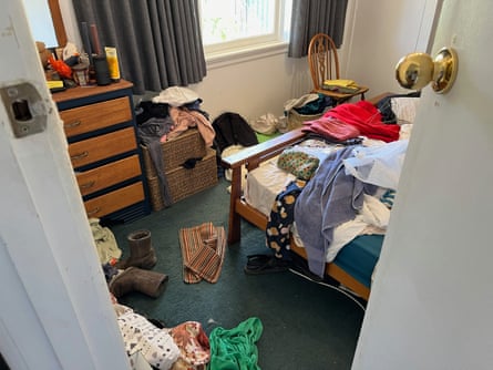 A view from the door, looking into to a disorganised bedroom with clothes on the bed and floor. 