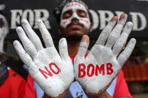 Mumbai, India. A man with his face and hands painted white shows the palms of his hands on which the words ‘No Bomb’ are written in red