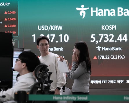 Currency traders talk near a screen showing KOSPI and dollar-won exchange figures at Hana Bank
