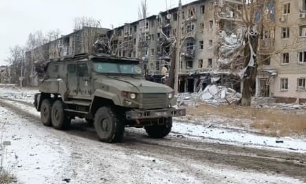 A Russian military vehicle drives past damaged residential buildings in Avdiivka.