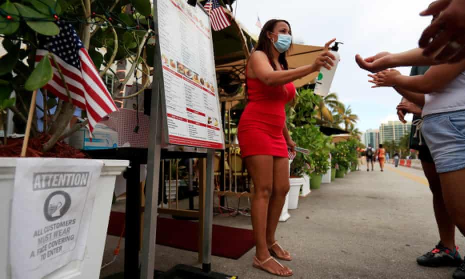 A hostess provides hand sanitizer to patrons entering a restaurant in Miami Beach, Florida, on 3 July. 